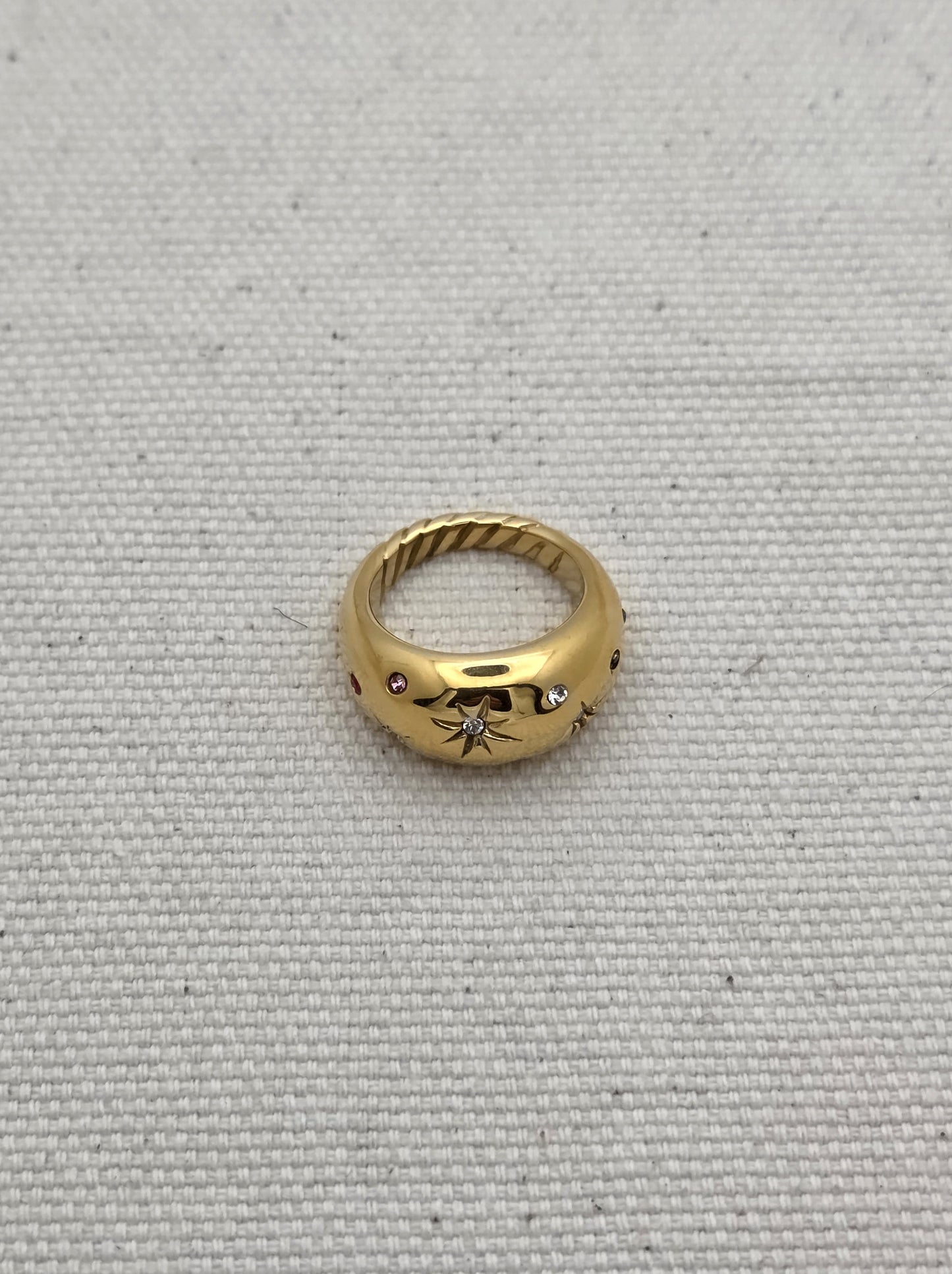 Anillo dorado con grabado de estrella central y piedras de colores – vista superior
