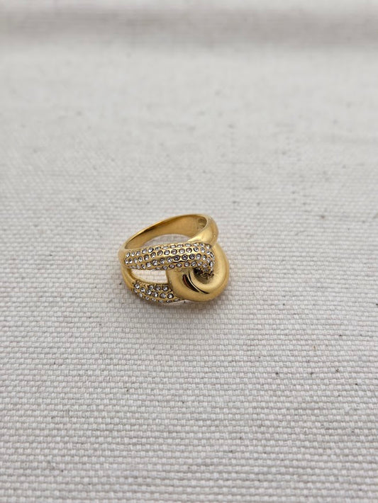 Anillo dorado con forma de nudo y cristales brillantes