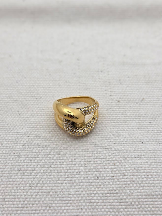 Vista frontal de anillo dorado con cristales y diseño anudado