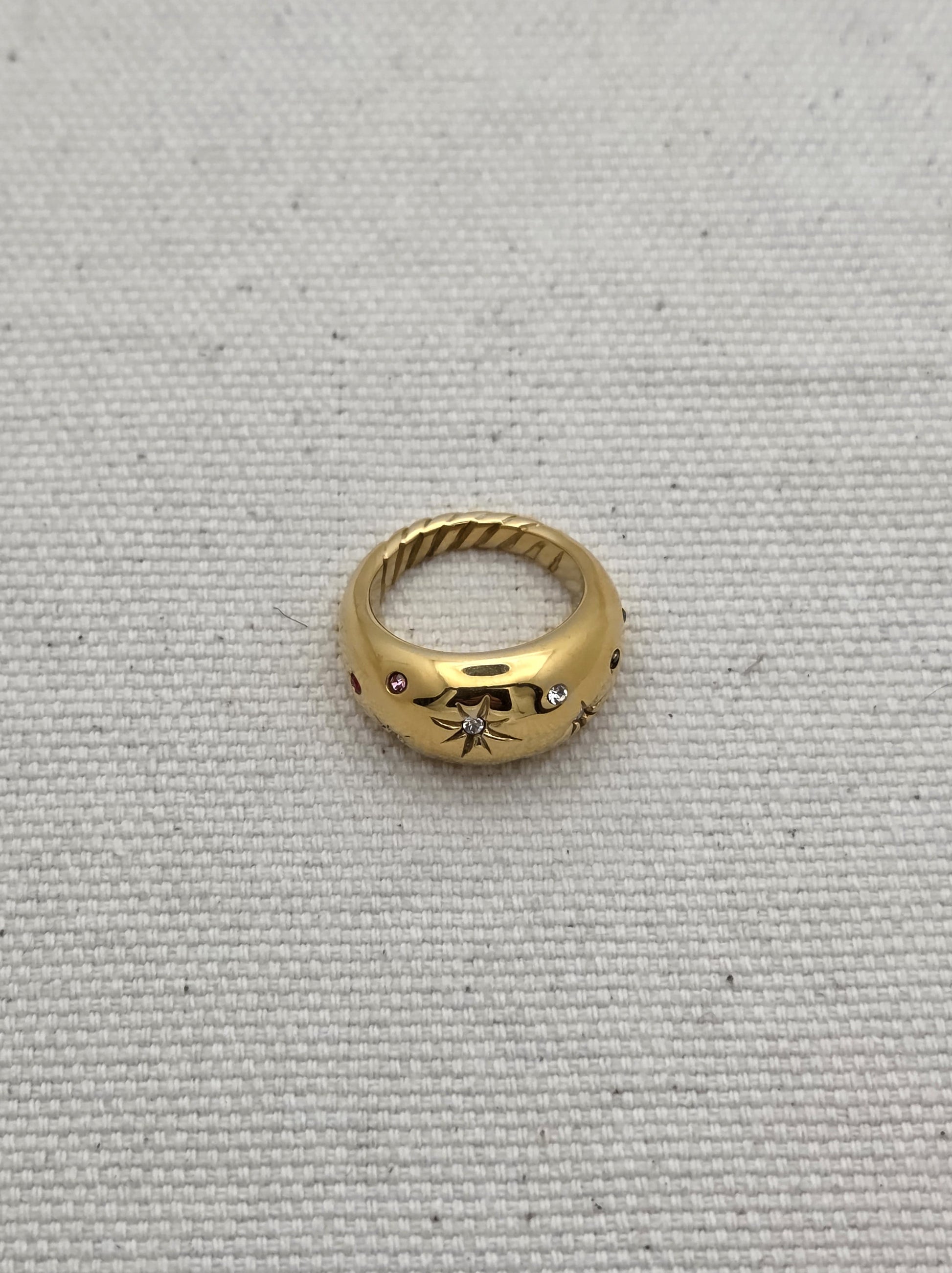 Anillo dorado con grabado de estrella central y piedras de colores – vista superior